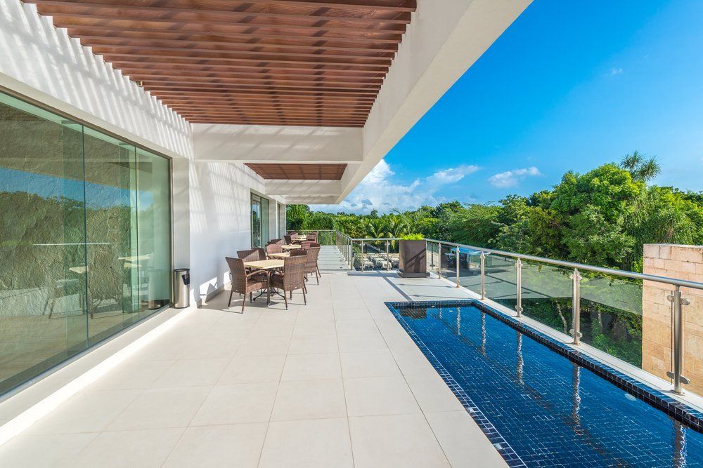 A Large Balcony with A Swimming Pool and Tables and Chairs — Glass Pool Fencing Australia in Hallidays Point, NSW