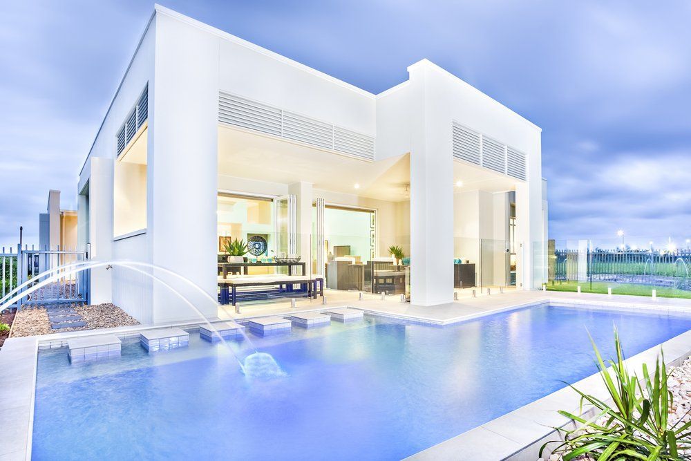 A White House with A Large Swimming Pool in Front of It — Glass Pool Fencing Australia in Newcastle, NSW