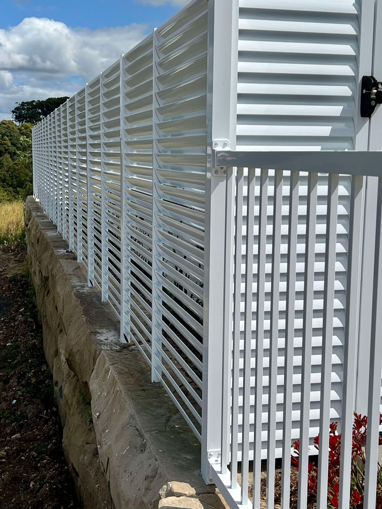 A white fence with shutters on it is sitting next to a concrete wall.— Glass Pool Fencing Australia in Old Bar, NSW