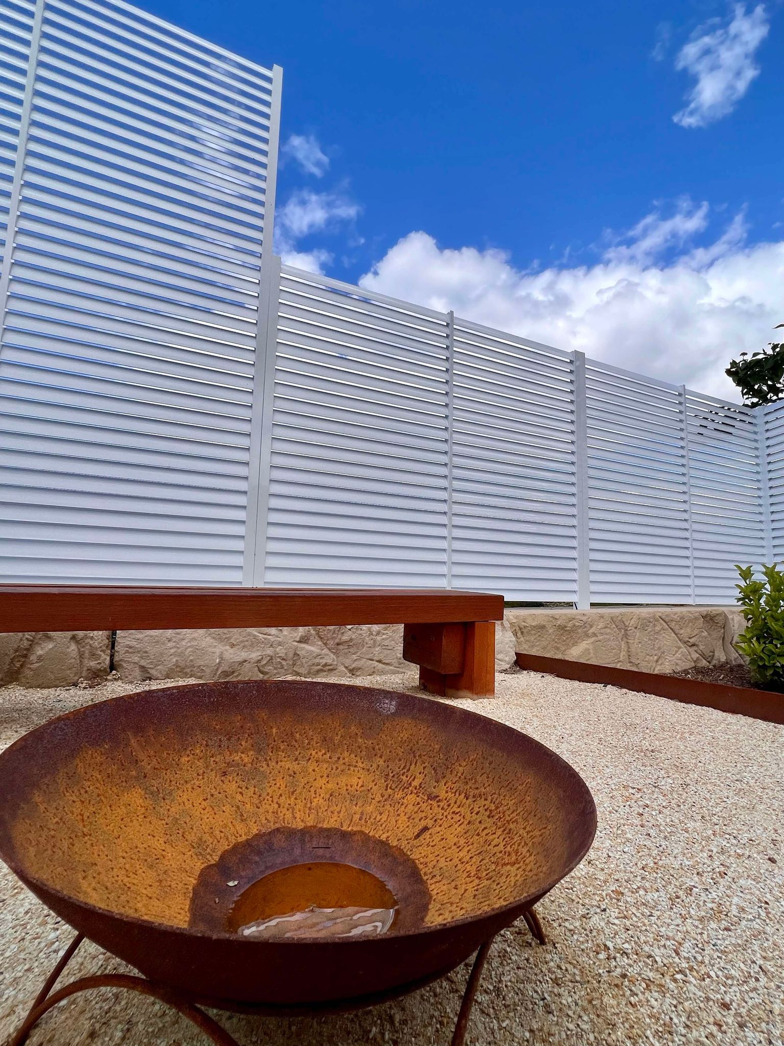 A Black Wrought Iron Fence Is Surrounded by Trees on A Sidewalk — Glass Pool Fencing Australia in Old Bar, NSW