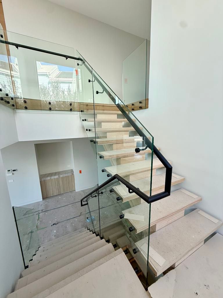 A Modern Staircase with White Stone Steps and A Glass Railing — Coastline Glass Pool Fencing in Old Bar, NSW