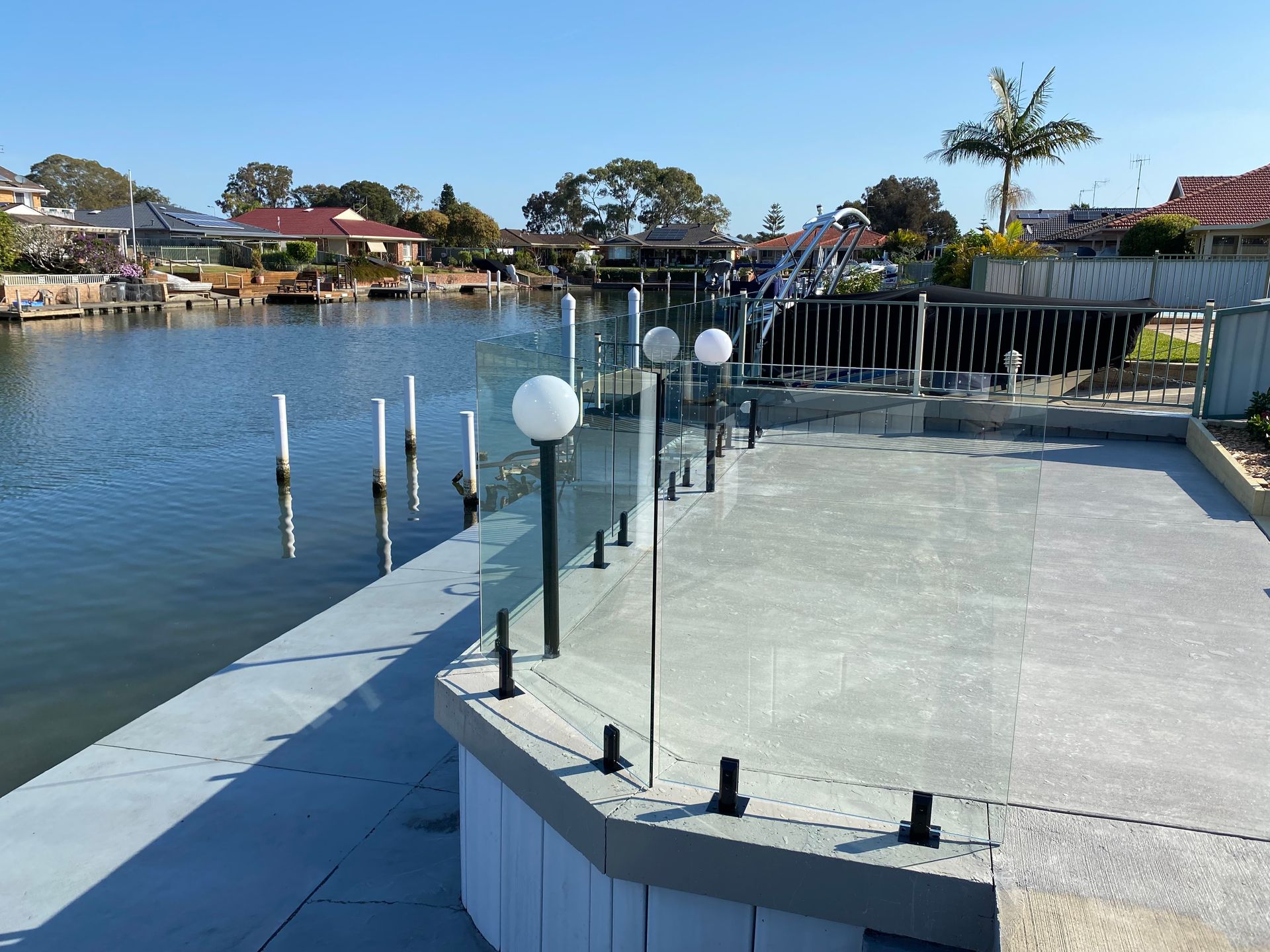 A dock with a glass railing overlooking a body of water — Glass Pool Fencing Australia in Old Bar, NSW