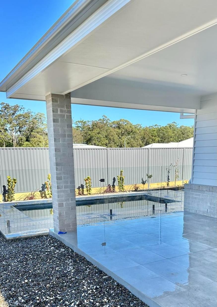 There Is A Swimming Pool In The Backyard Of A House — Glass Pool Fencing Australia in Old Bar, NSW