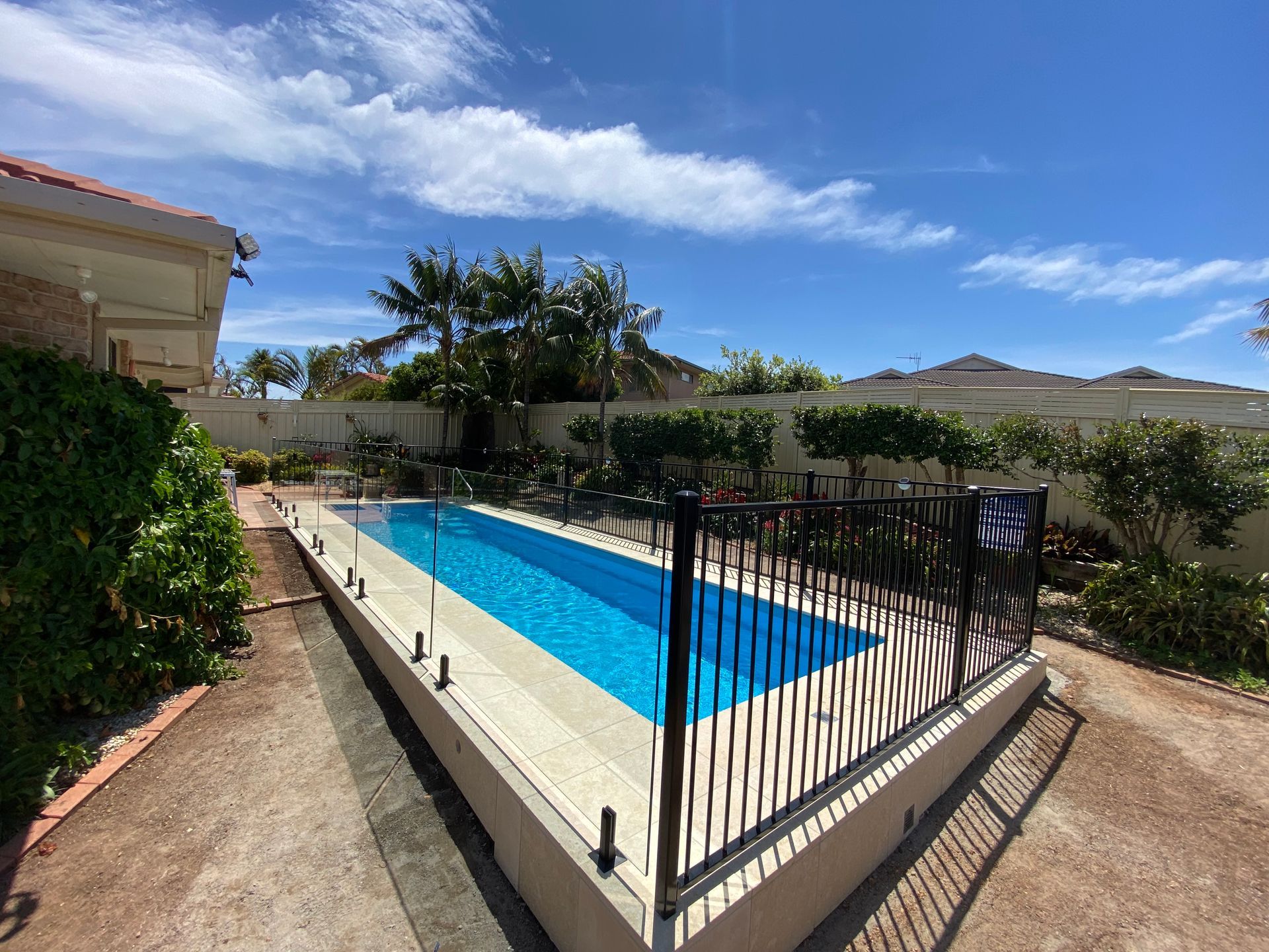 A modern house with a swimming pool and a wooden deck — Glass Pool Fencing Australia in Old Bar, NSW
