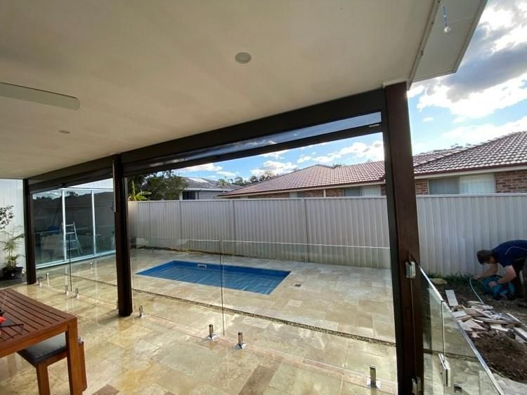 A Man Is Working On A Fence Around A Swimming Pool — Glass Pool Fencing Australia in Old Bar, NSW