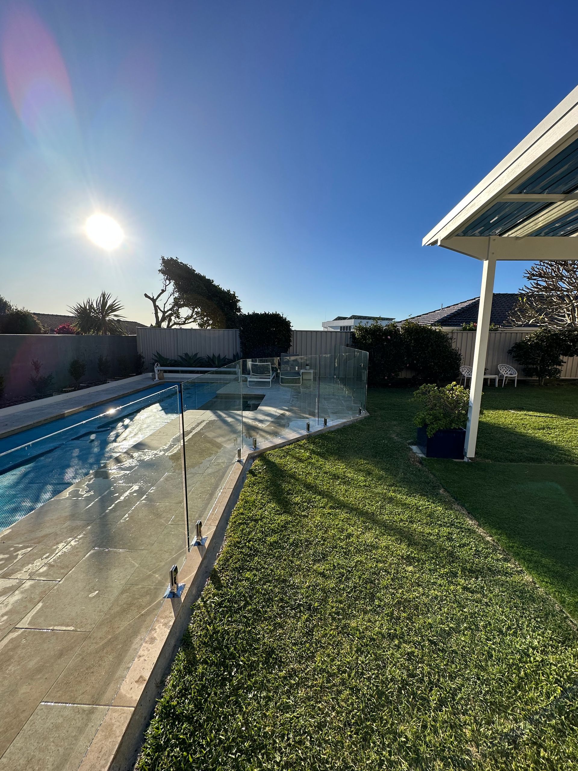 A Modern House with A Swimming Pool and A Wooden Deck — Glass Pool Fencing Australia in Coffs Harbour, NSW