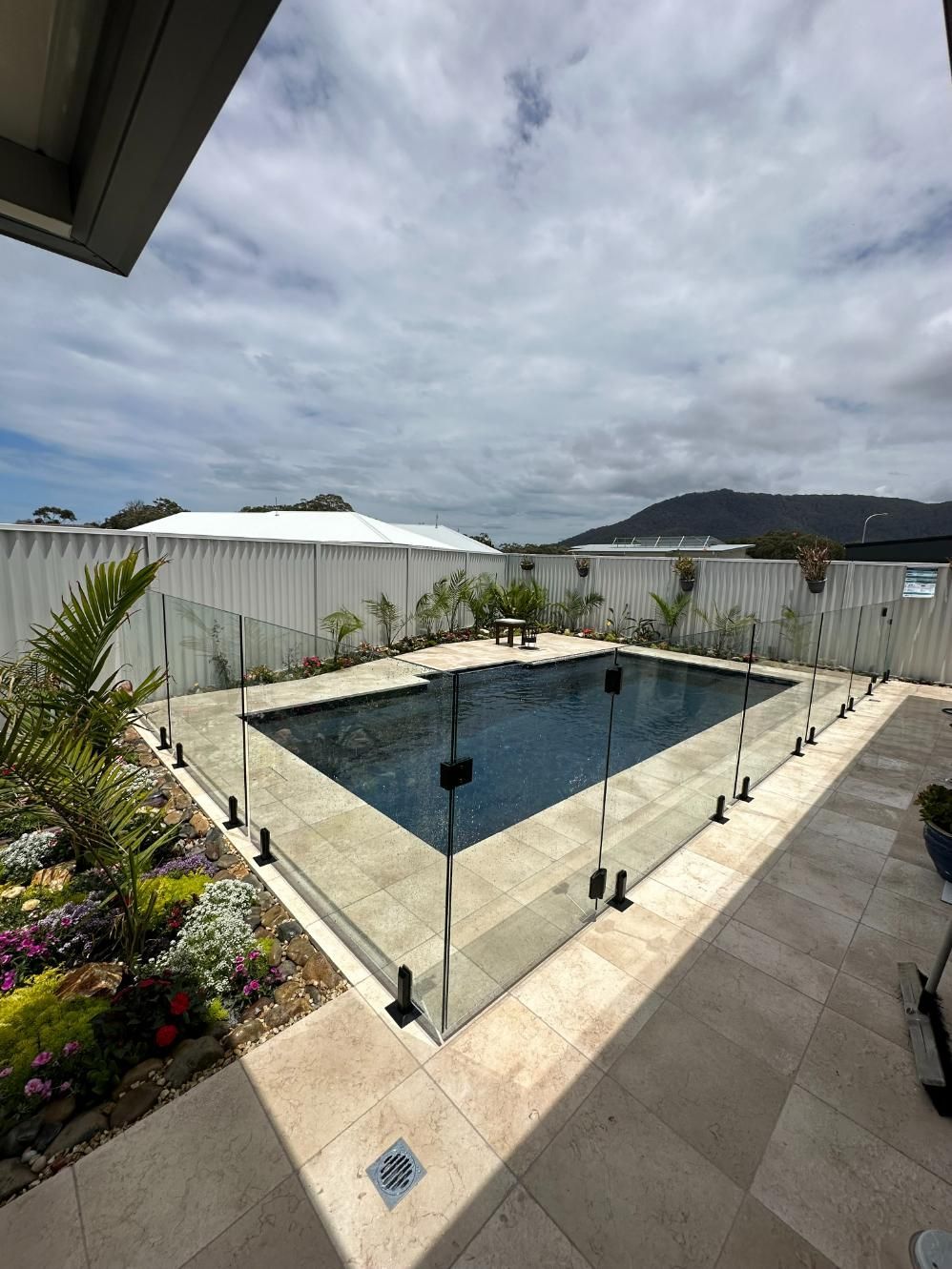 A Large Swimming Pool With A Glass Fence Around It — Glass Pool Fencing Australia in Old Bar, NSW