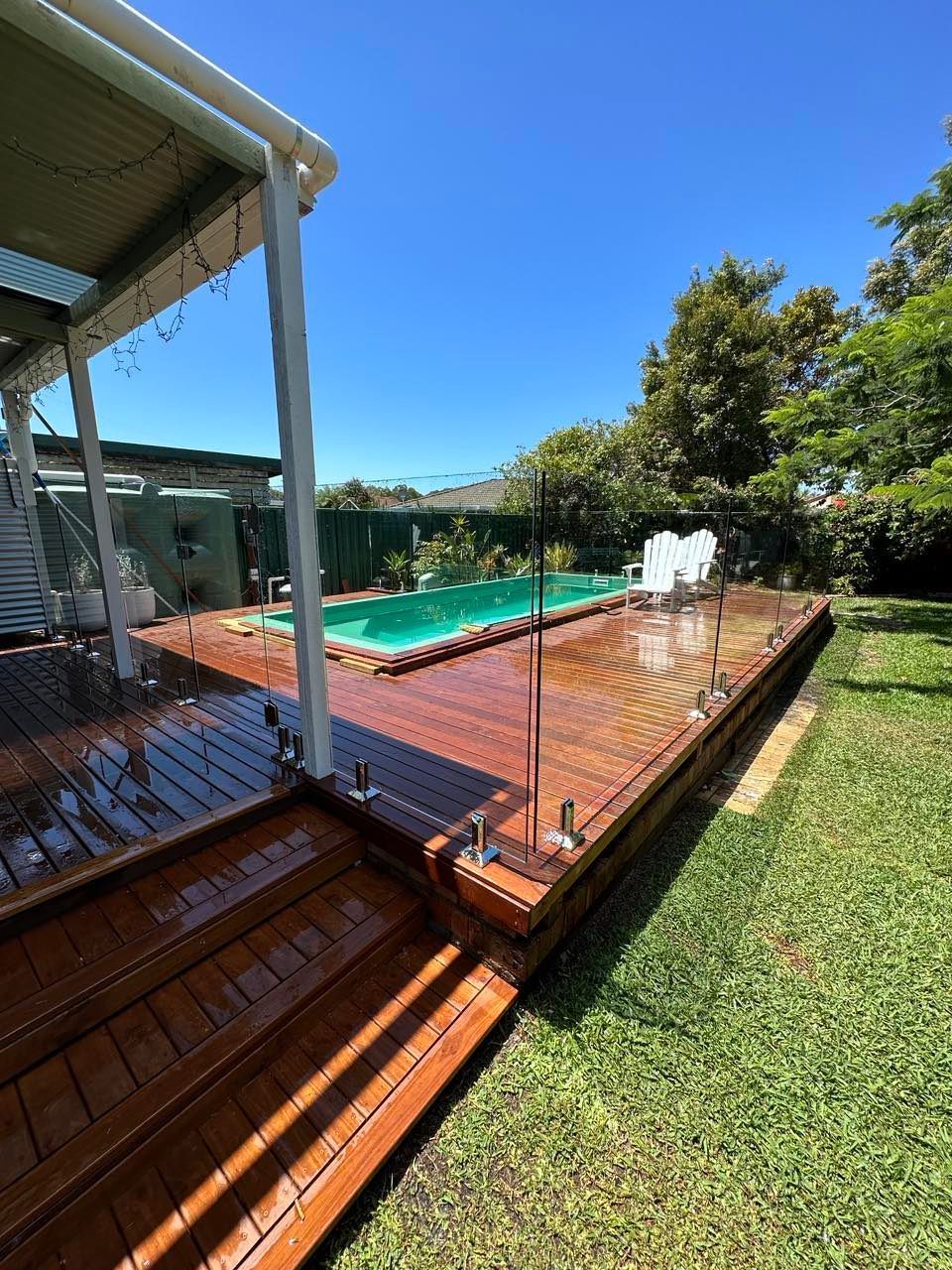 A Large Swimming Pool Surrounded by Chairs and A Fence — Glass Pool Fencing Australia in Old Bar, NSW