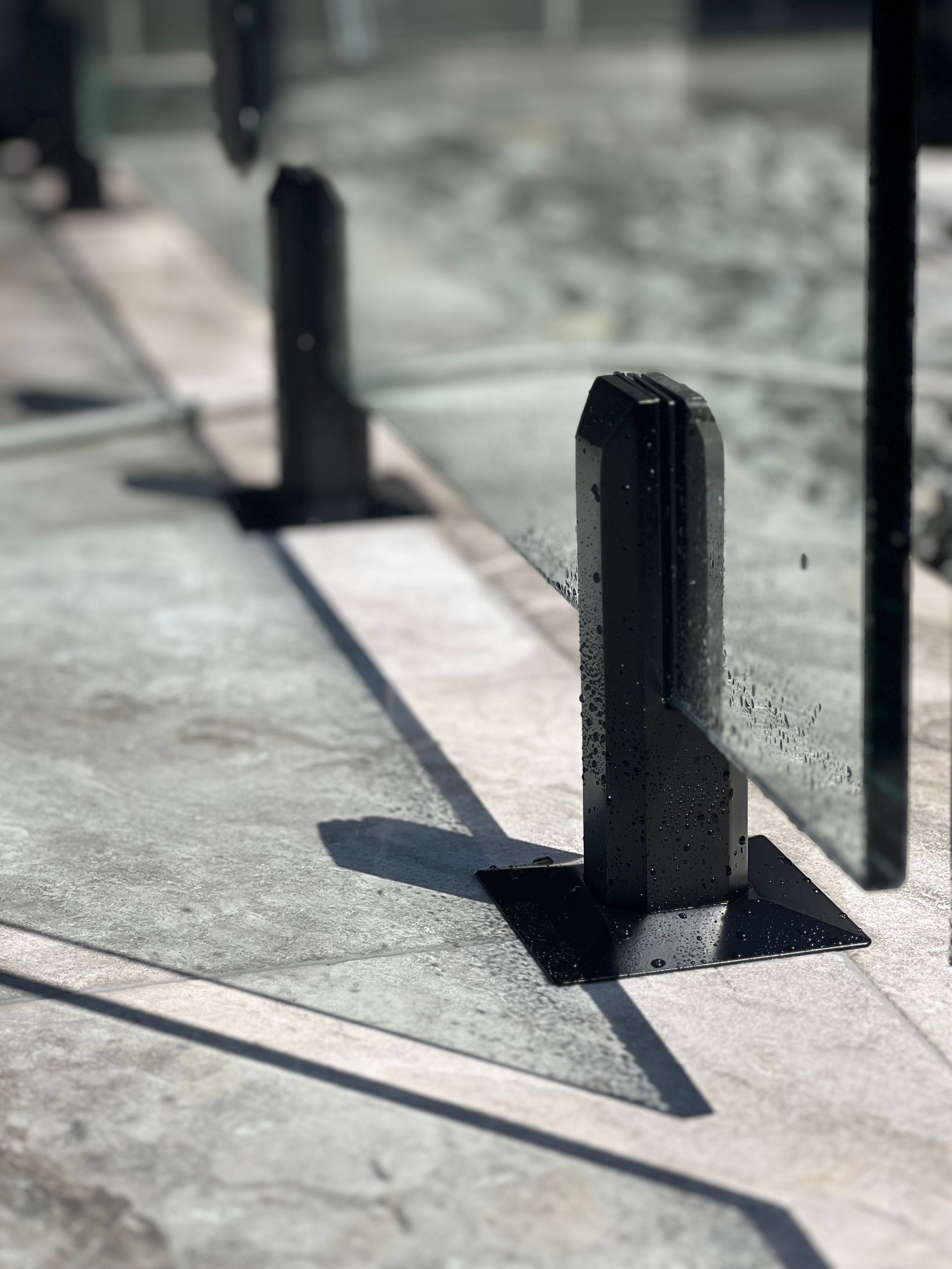 A close up of a glass fence with a shadow on the ground.— Glass Pool Fencing Australia in Old Bar, NSW