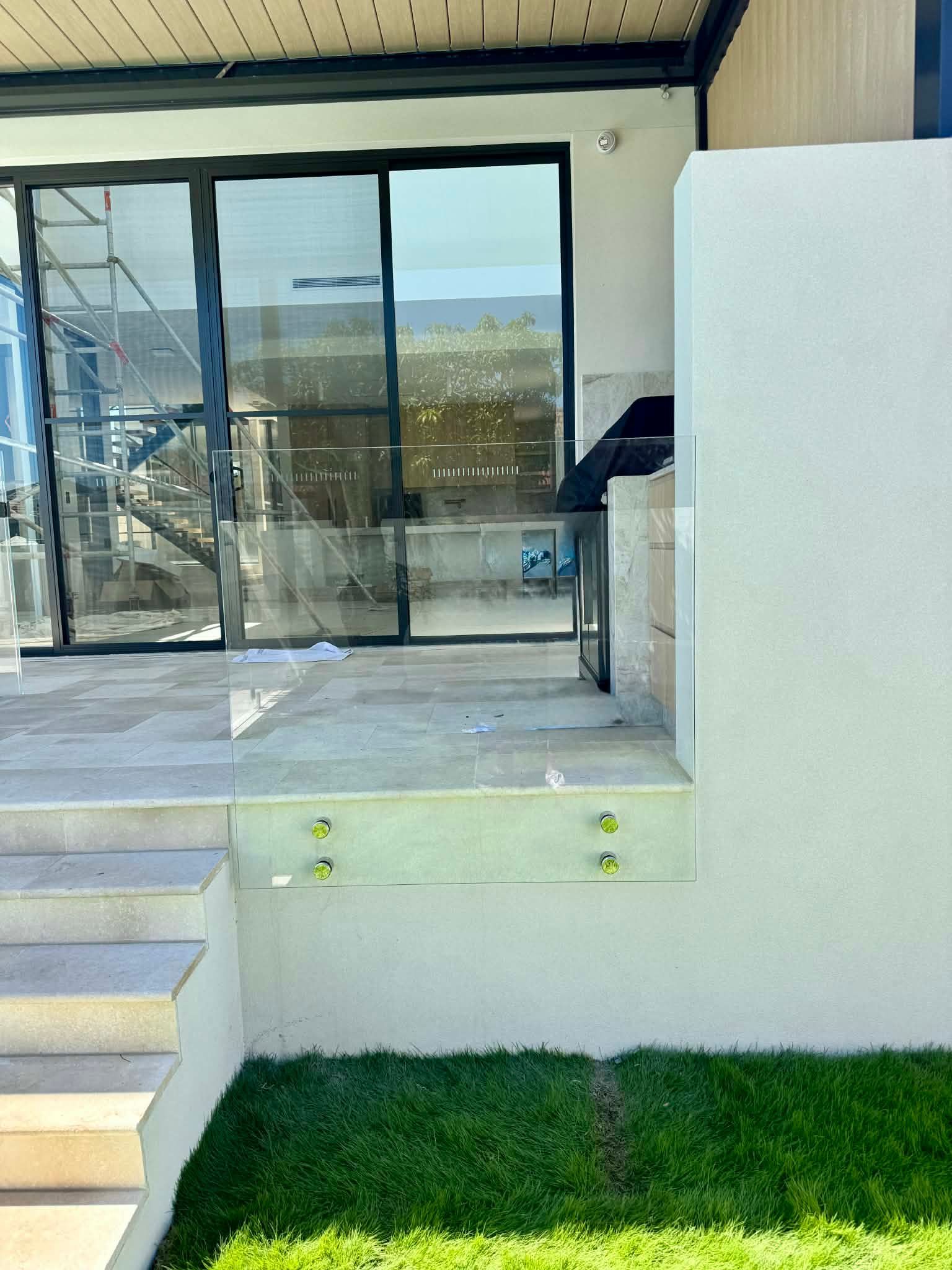 A Glass Safety Railing Installed on The Edge of An Outdoor Patio — Coastline Glass Pool Fencing in Old Bar, NSW