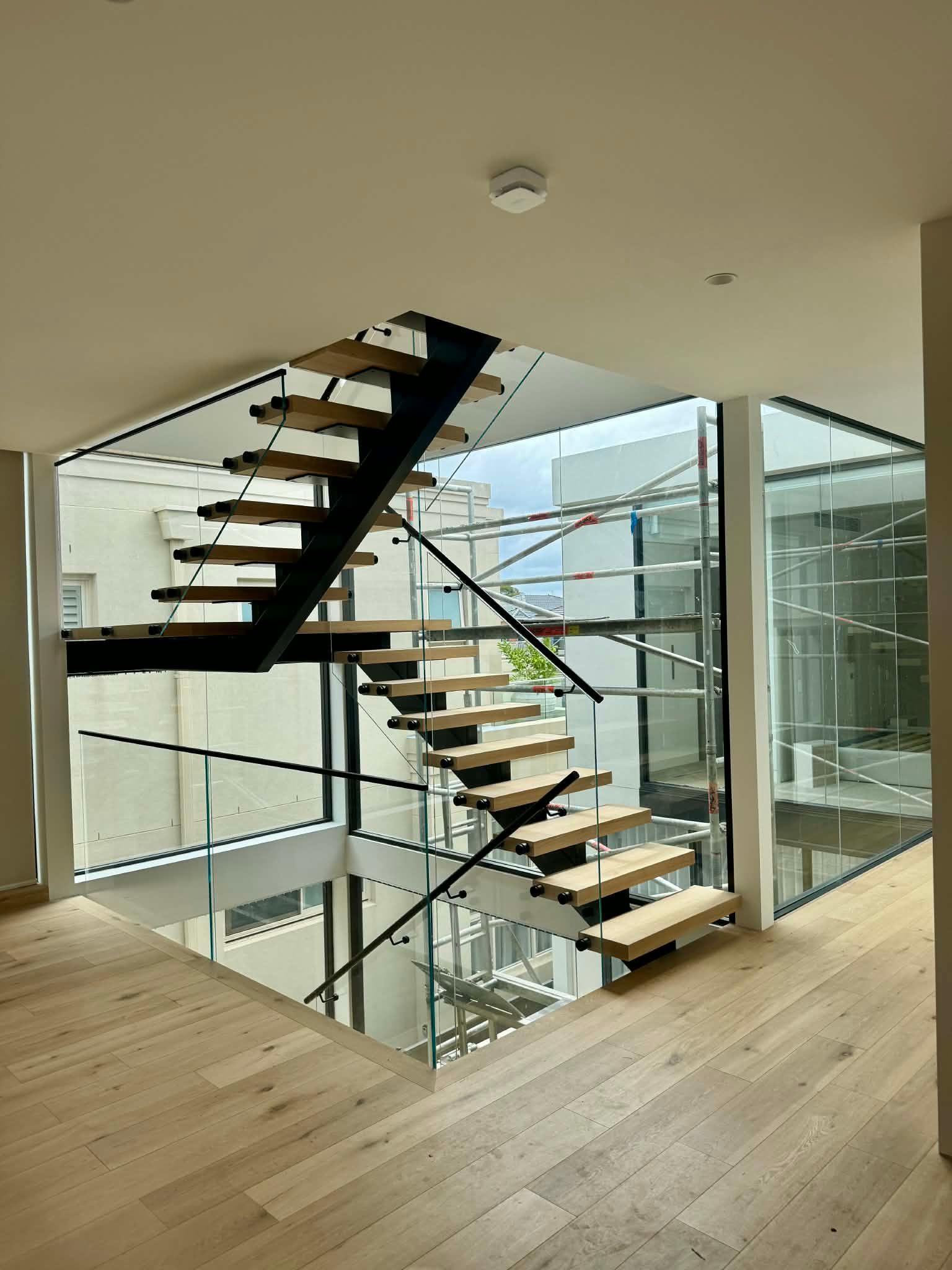 A Modern Staircase with Wooden Treads and A Black Metal Frame — Coastline Glass Pool Fencing in Old Bar, NSW