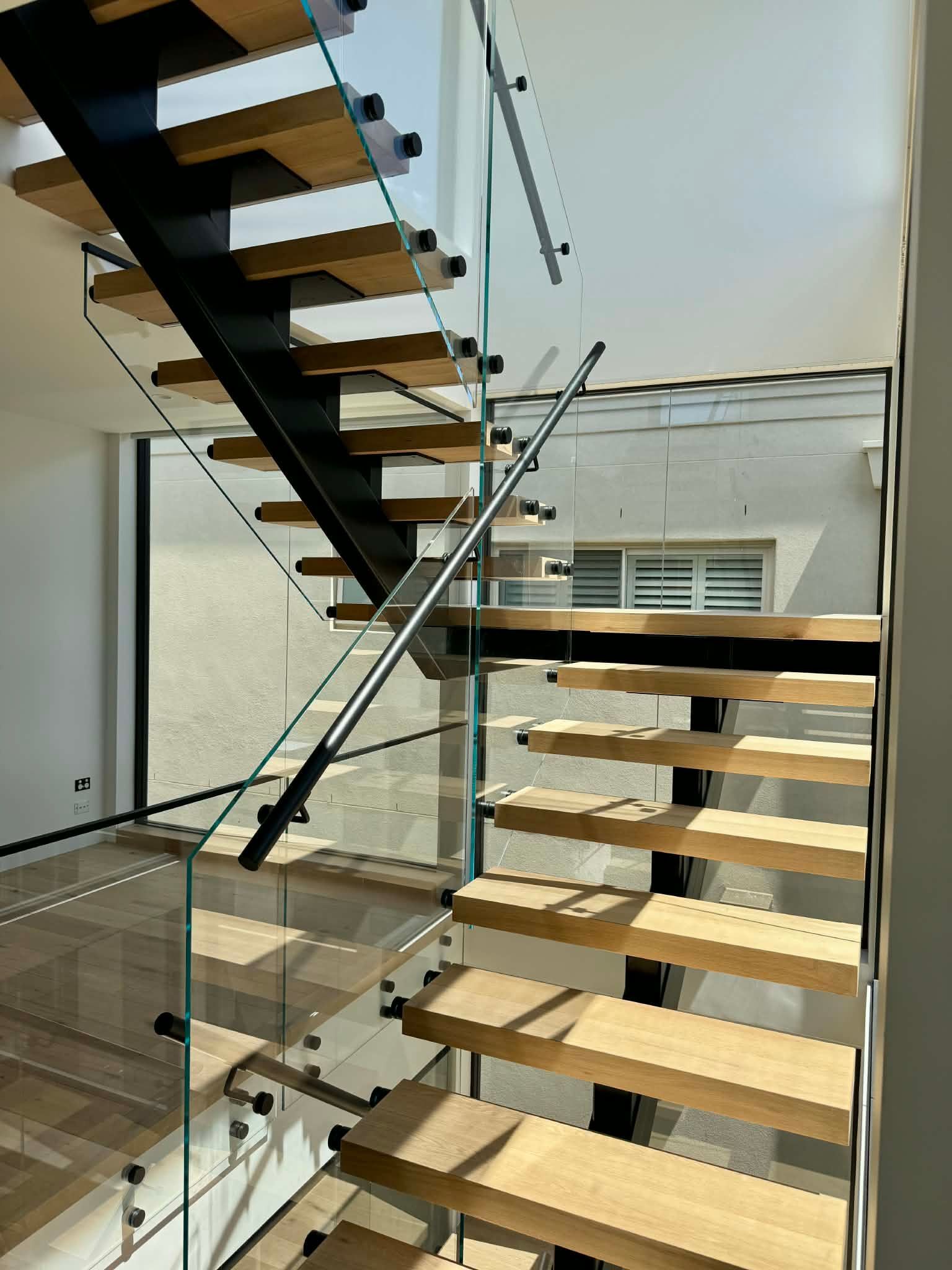 Modern Staircase with Wooden Treads and A Black Metal Frame — Coastline Glass Pool Fencing in Old Bar, NSW