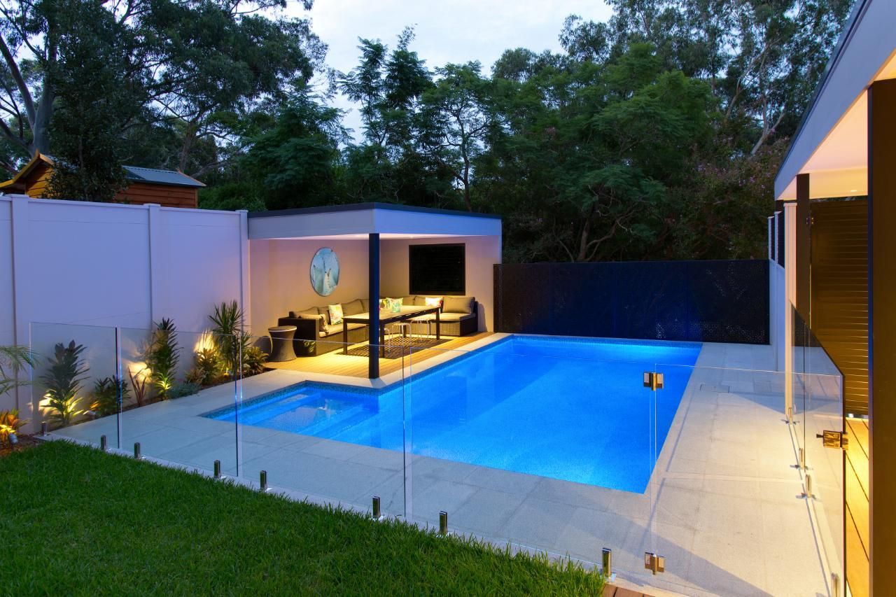 A Large Swimming Pool Is In The Backyard Of A House — Glass Pool Fencing Australia in Old Bar, NSW