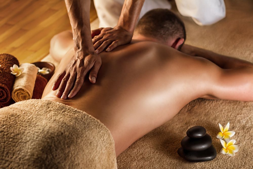 A Man is Getting a Massage With Towels and Stones on the Side — Siam Thai Massage In Tweed Heads, NSW