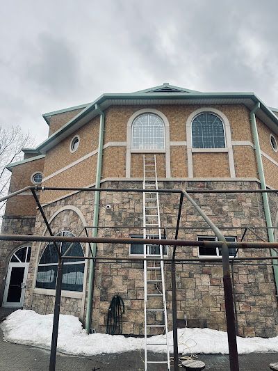 Man in blue gloves, installing a light fixture in a modern kitchen.