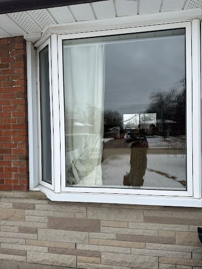 A large bay window with white frames set into a house exterior featuring brick siding and stone veneer.