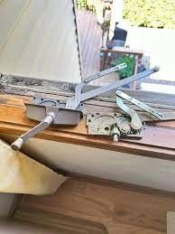 Two metal casement window crank operators resting on a wooden windowsill.