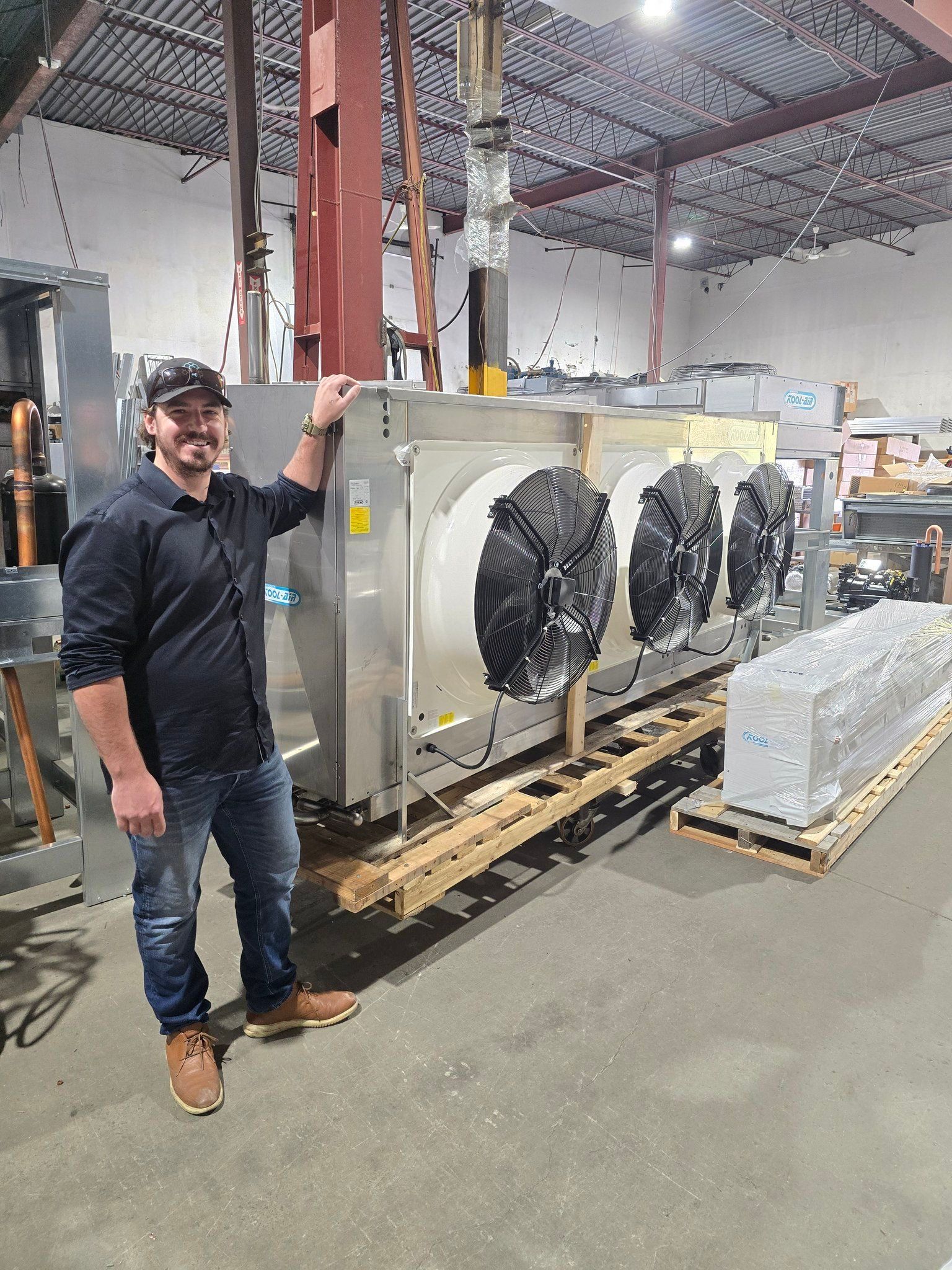 Un homme se tient devant une grande machine dans un entrepôt.