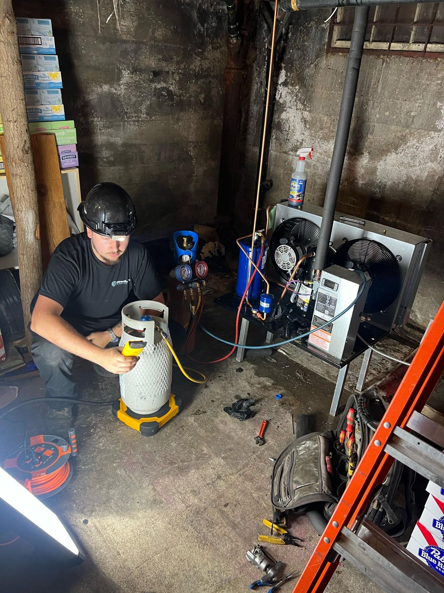 Un homme travaille sur un climatiseur dans un sous-sol.