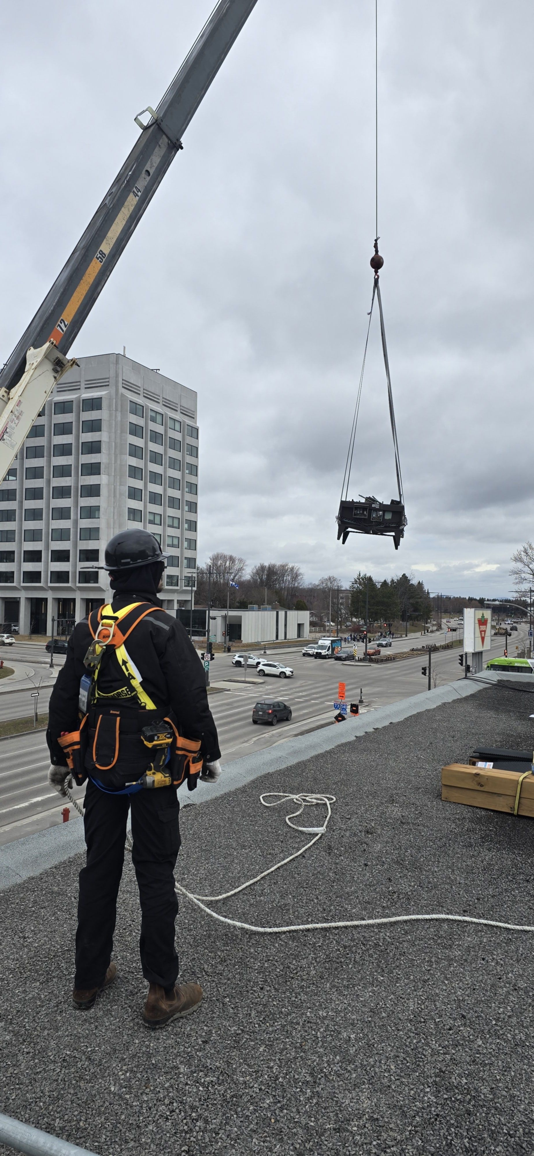 Un homme se tient debout sur un toit à côté d'une grue.