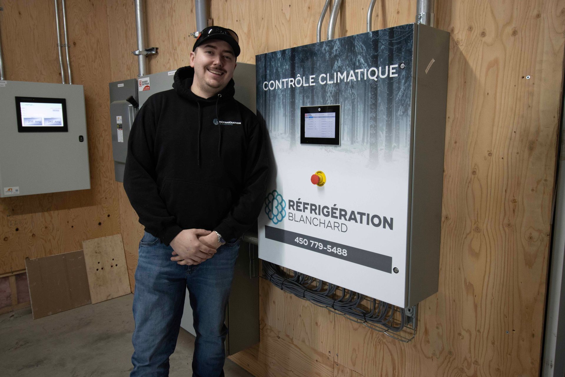 Un homme se tient devant un panneau de contrôle.