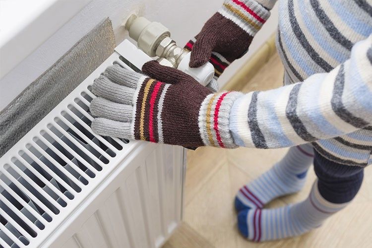 Une personne portant des gants ajuste un radiateur.