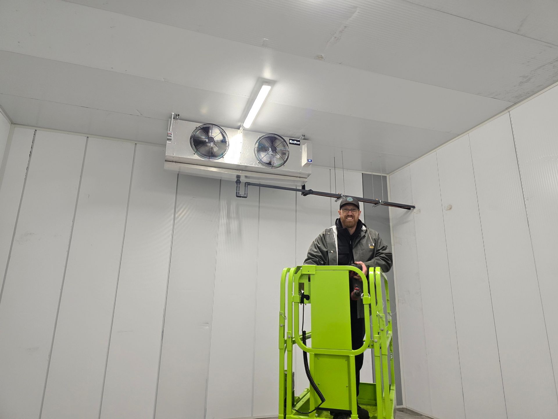 Un homme se tient debout sur un ascenseur vert dans une pièce.