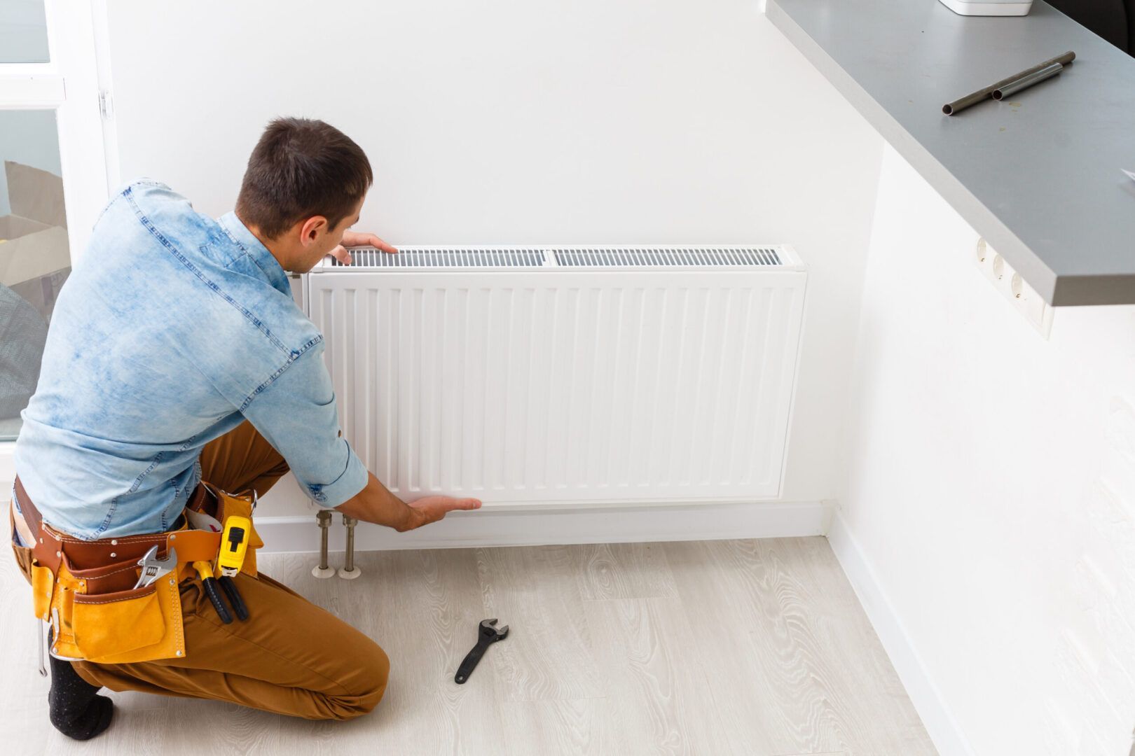 Un homme mesure un radiateur avec un ruban à mesurer.