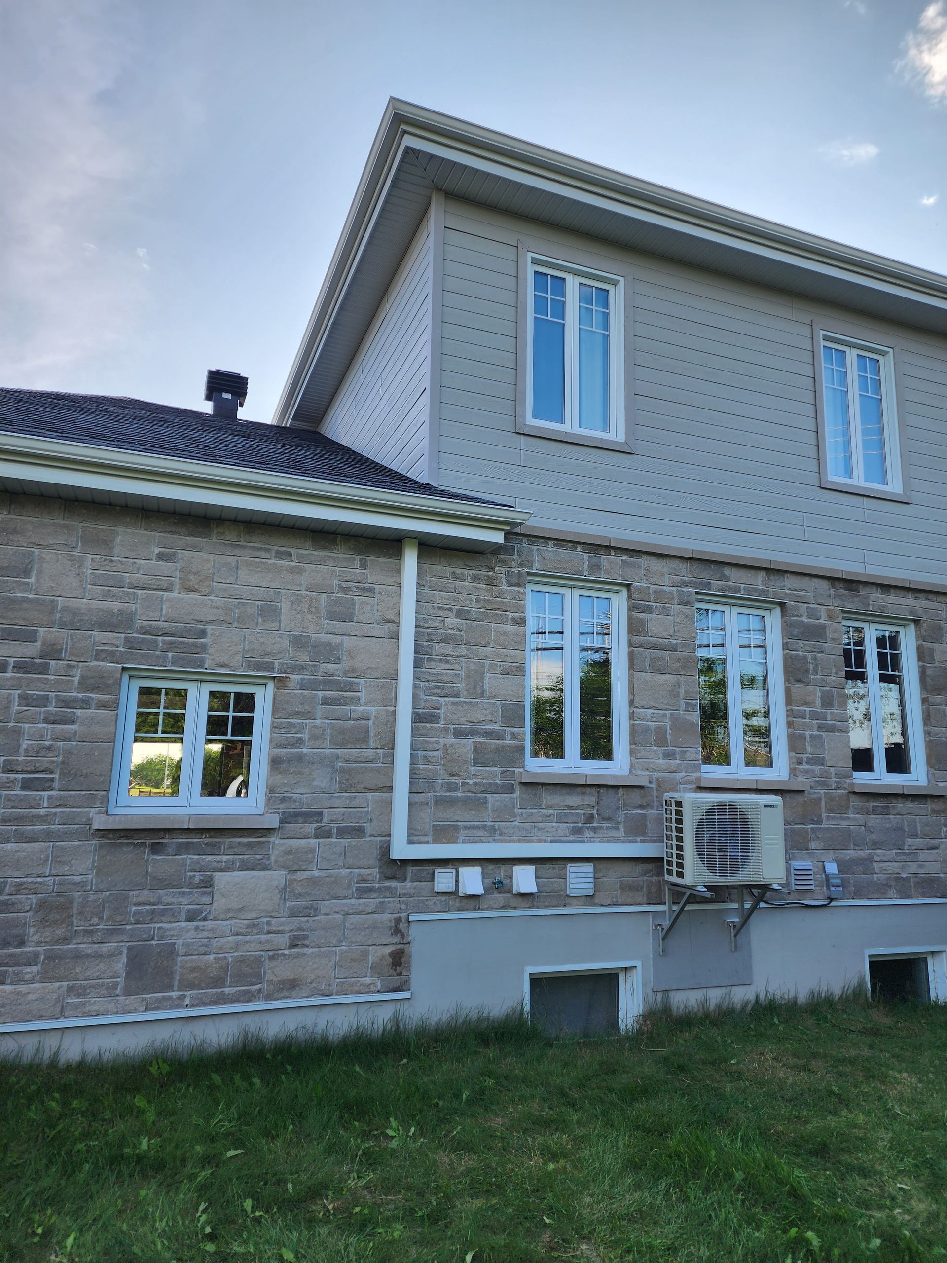 Une grande maison en brique avec beaucoup de fenêtres et un climatiseur sur le côté.