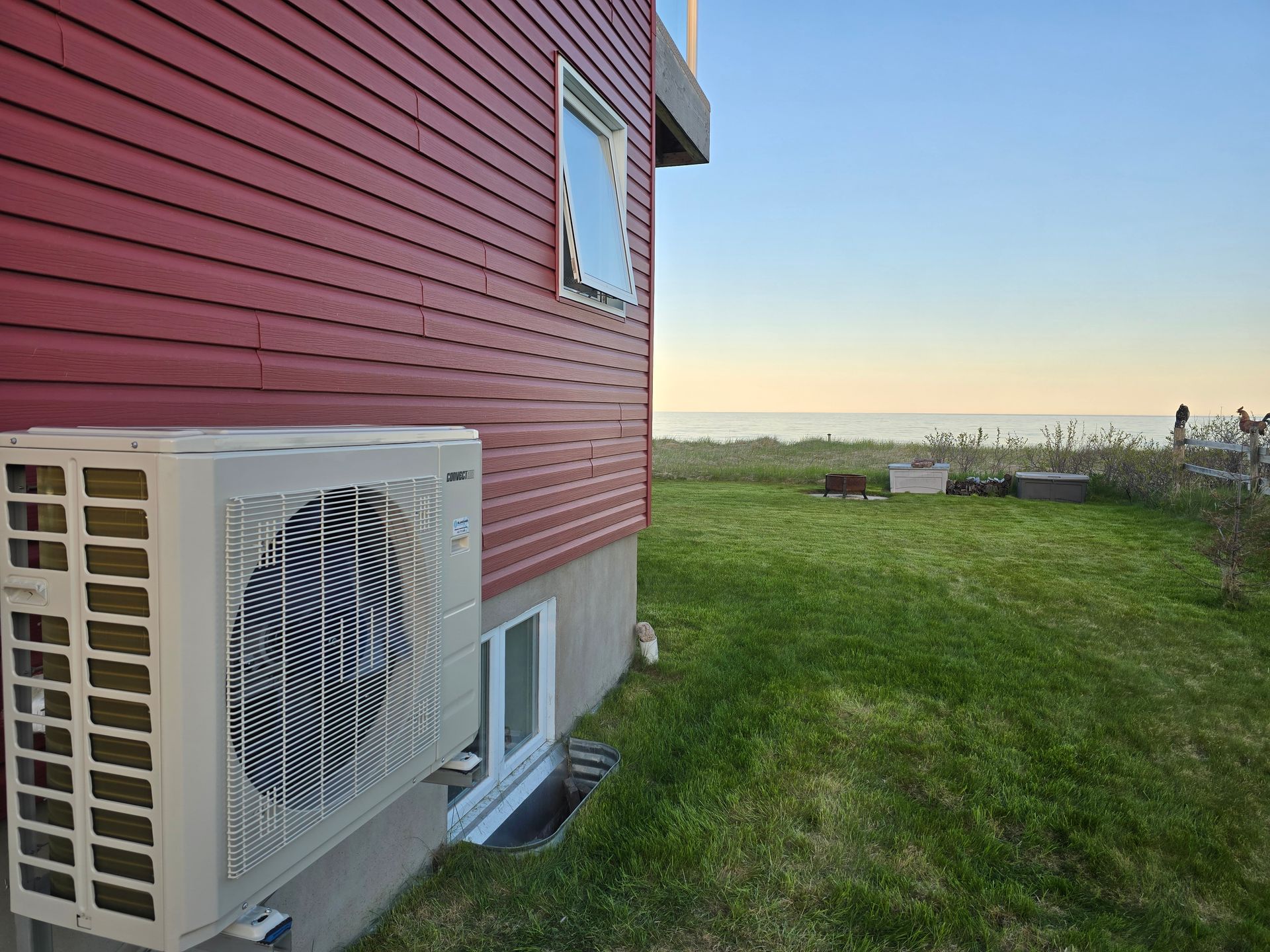 Une maison rouge avec un climatiseur blanc sur le côté.