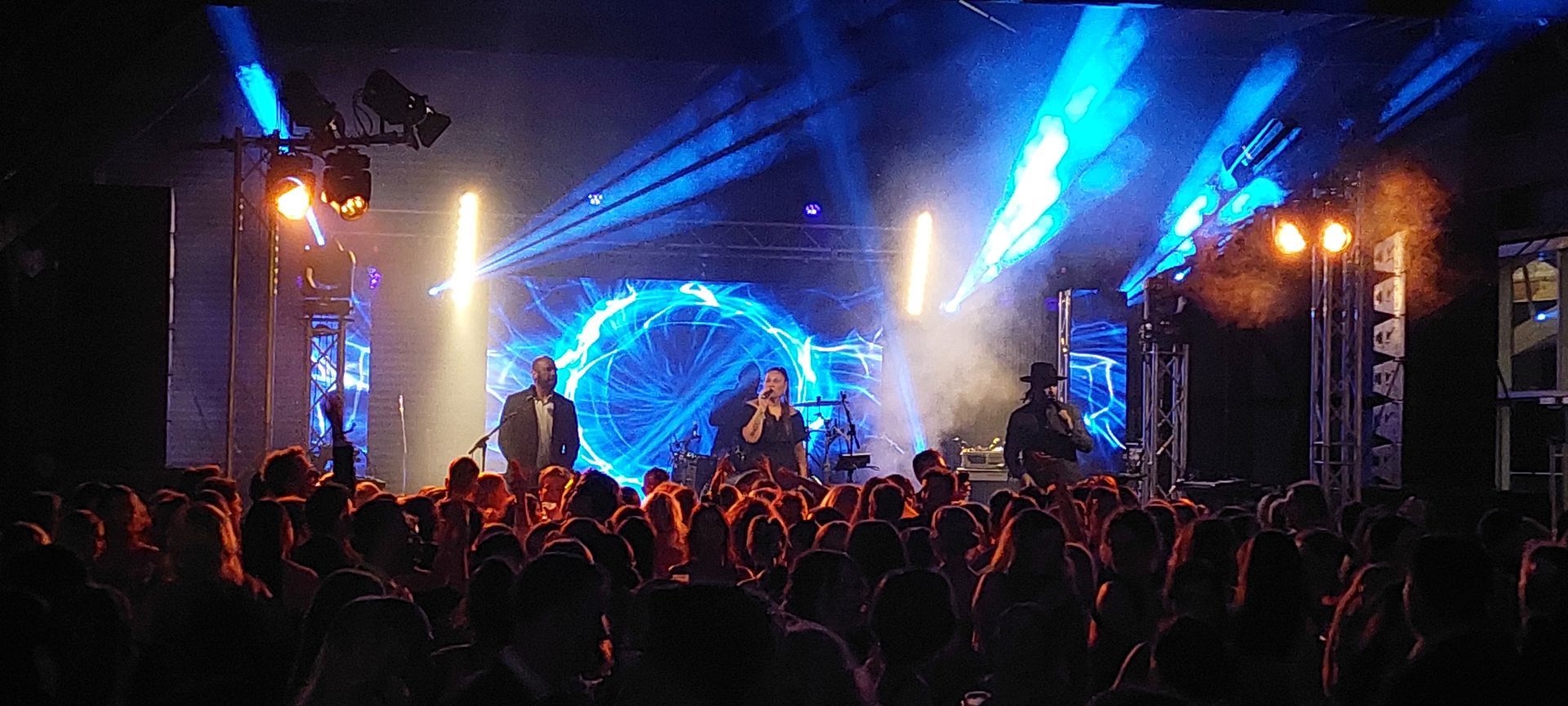 A crowd of people are watching a band on stage at a concert.