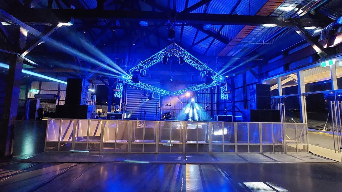 A large room with blue lights on the ceiling and a stage.