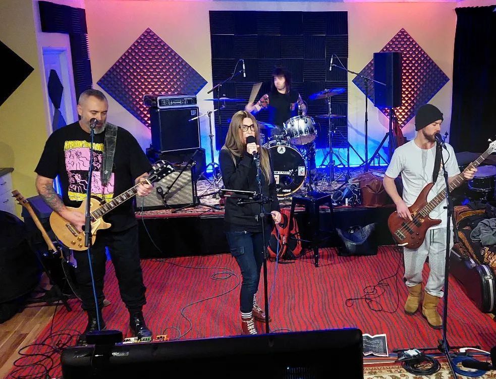 A group of people are playing instruments on a stage and singing into microphones.