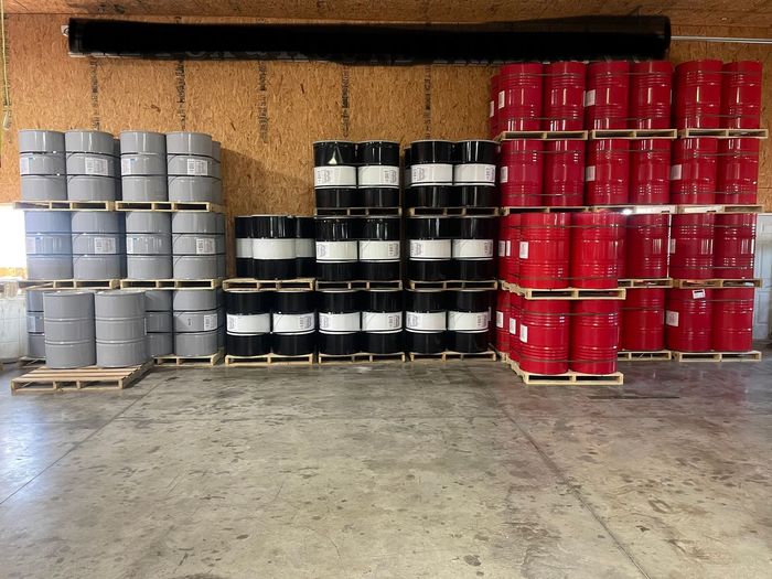 A bunch of barrels are stacked on pallets in a warehouse