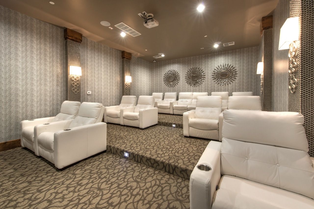 Communal cinema room with white recliner chairs and warm lighting.