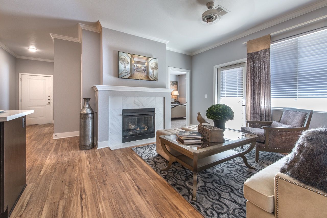 Living room with a gas fireplace, seating area, coffee table, and large windows.