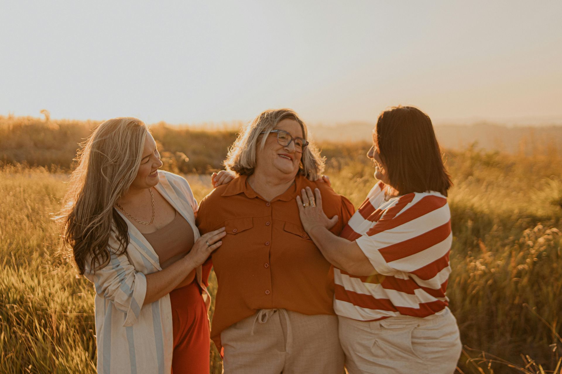 Three women are posing for a picture together and laughing.