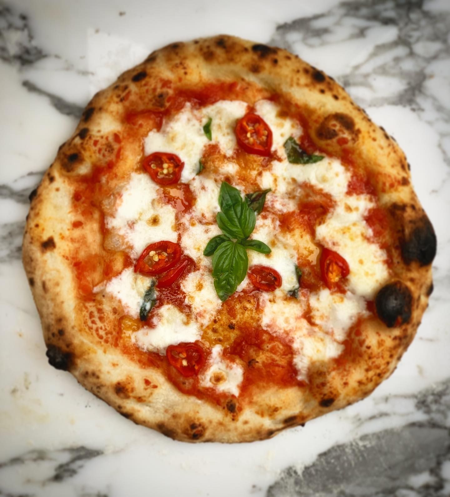 "Margherita pizza with tomato, mozzarella, pecorino, olive oil, fresh red chillies
 and basil 