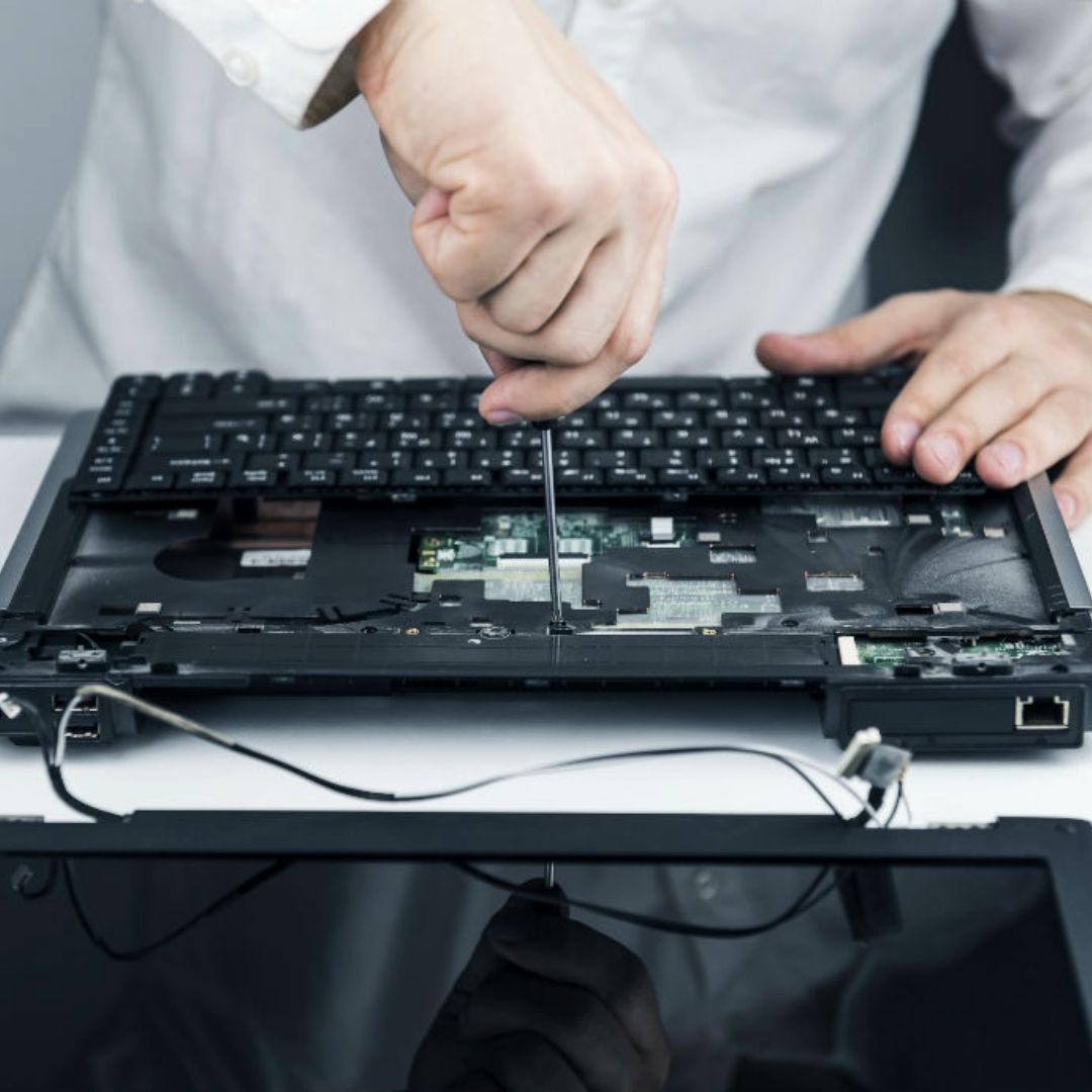 A person is working on a laptop with a screwdriver
