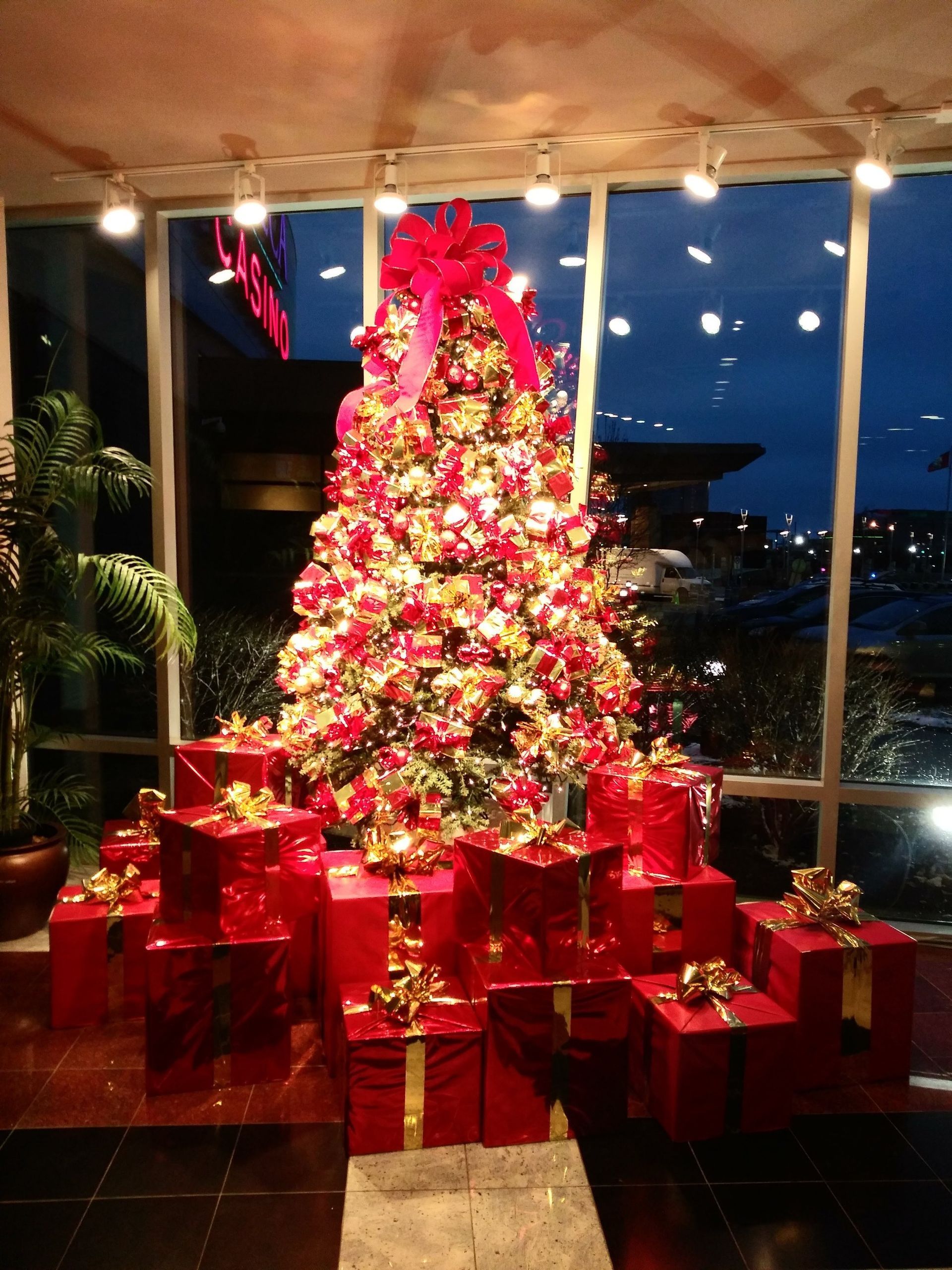 A christmas tree surrounded by presents in front of a window