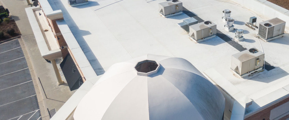 Aerial view of a white building with a domed roof and multiple square roof-mounted units.