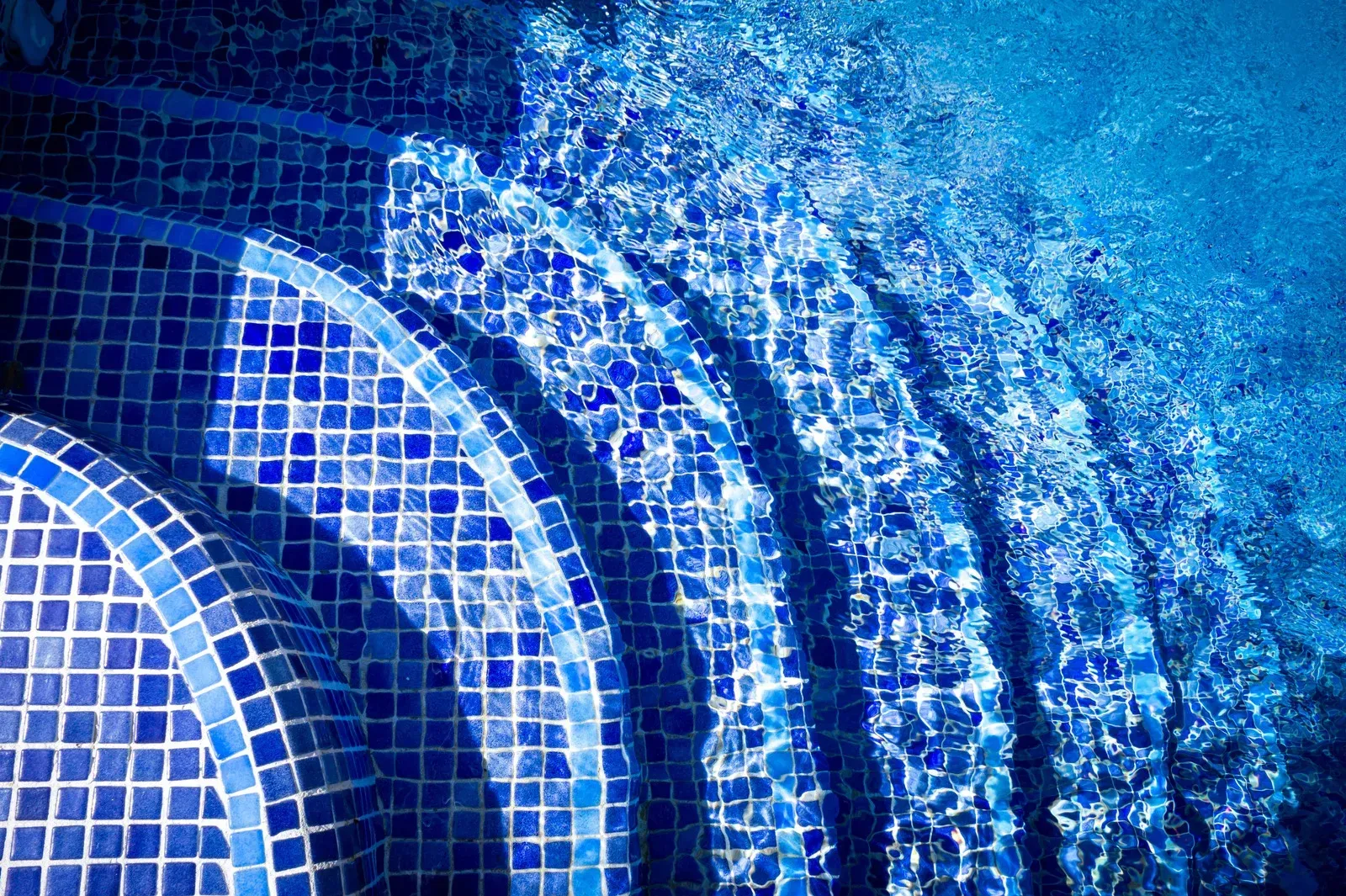 Blue tiled steps leading into a shimmering pool of water.