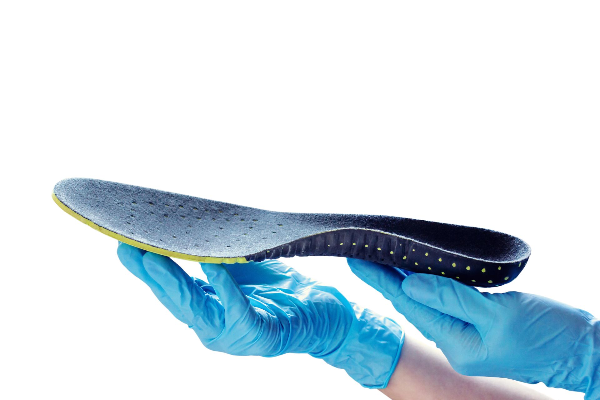 Mani con guanti medici blu che reggono una soletta scura e ruvida su sfondo bianco.