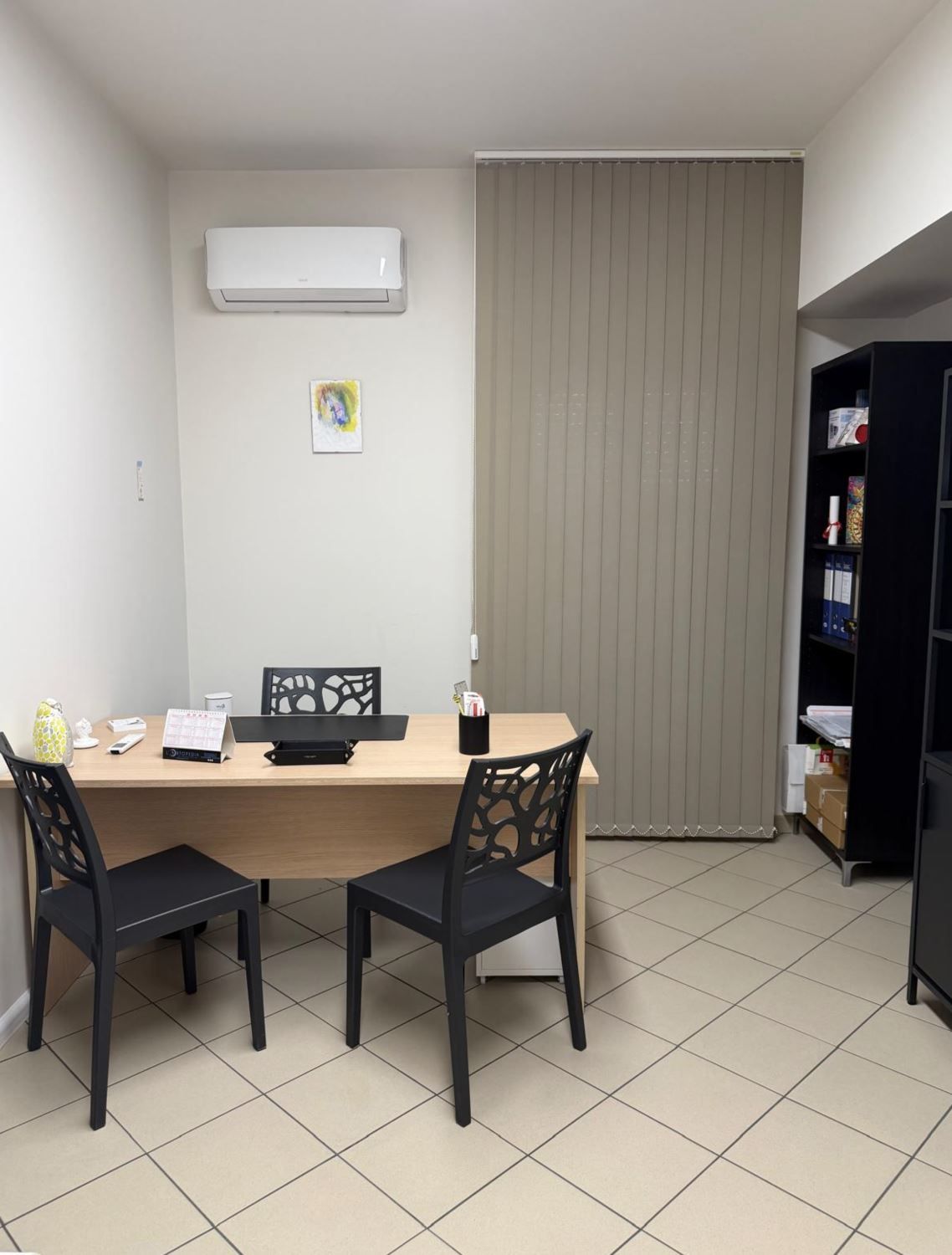 Un piccolo ufficio con una scrivania in legno chiaro, due sedie nere, 