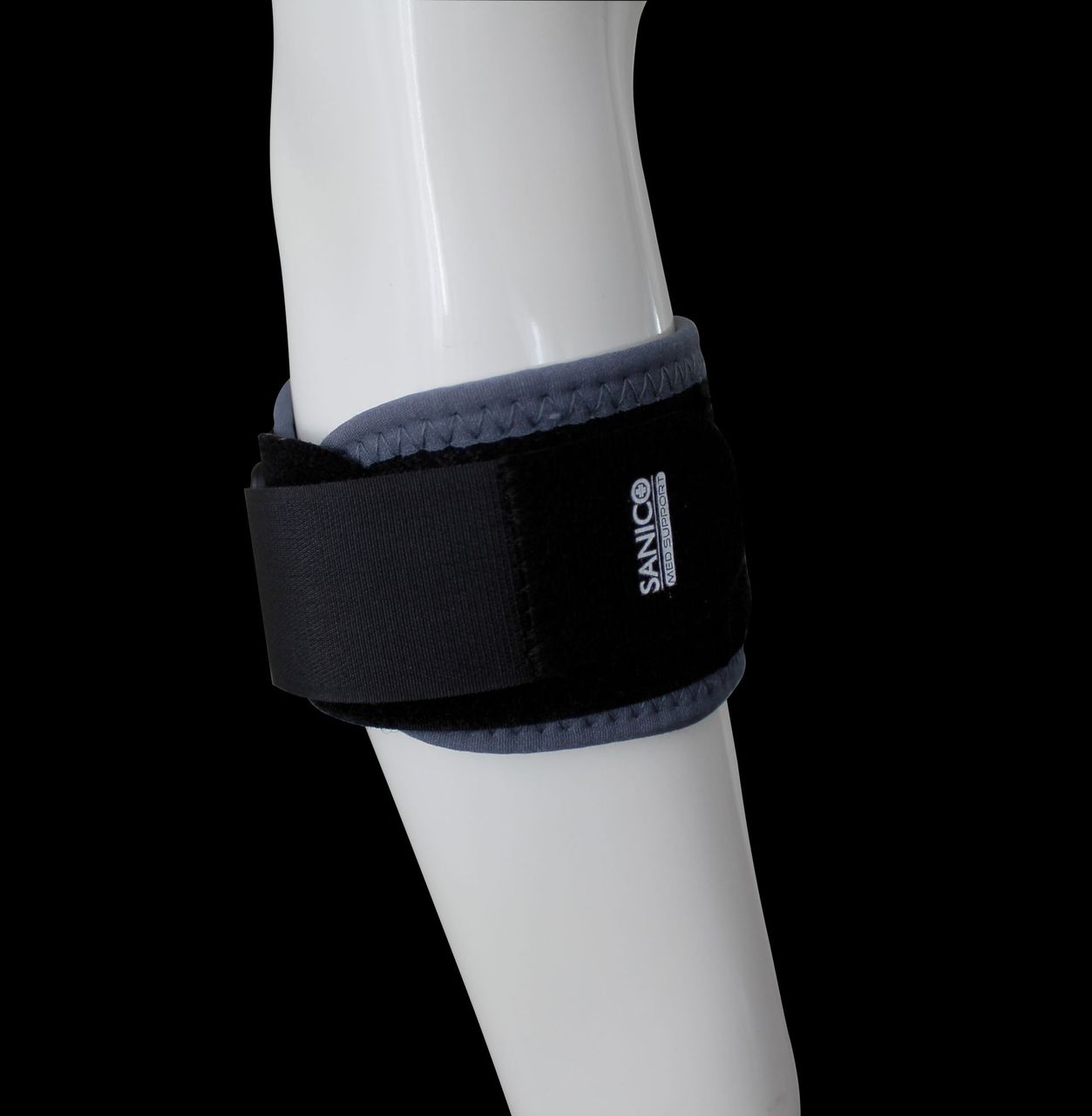 Una persona vista di spalle indossa un correttore posturale beige in maglia sopra una canottiera bianca.