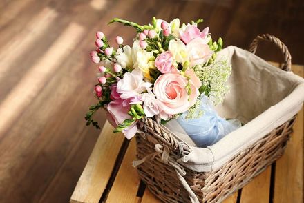 A basket filled with flowers is sitting on a wooden table.
