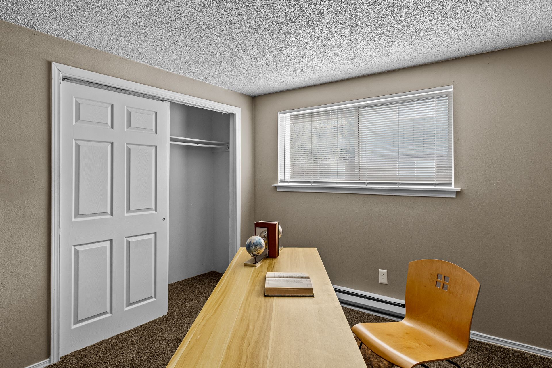 Small office room with desk, chair, closet, and window blinds