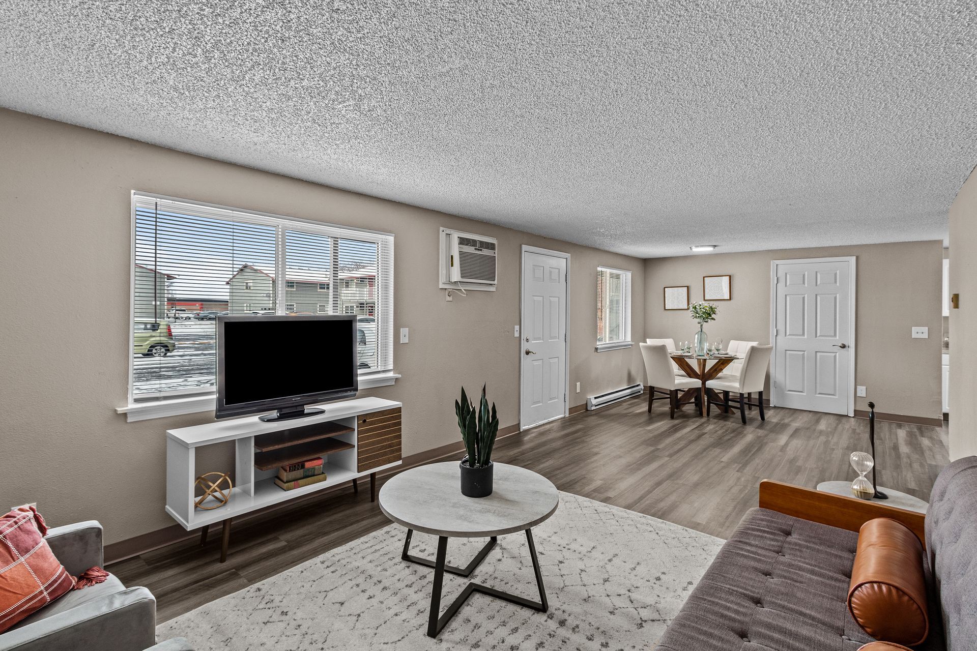 Bright living room with TV, sofa, coffee table, and dining area with wood floors.