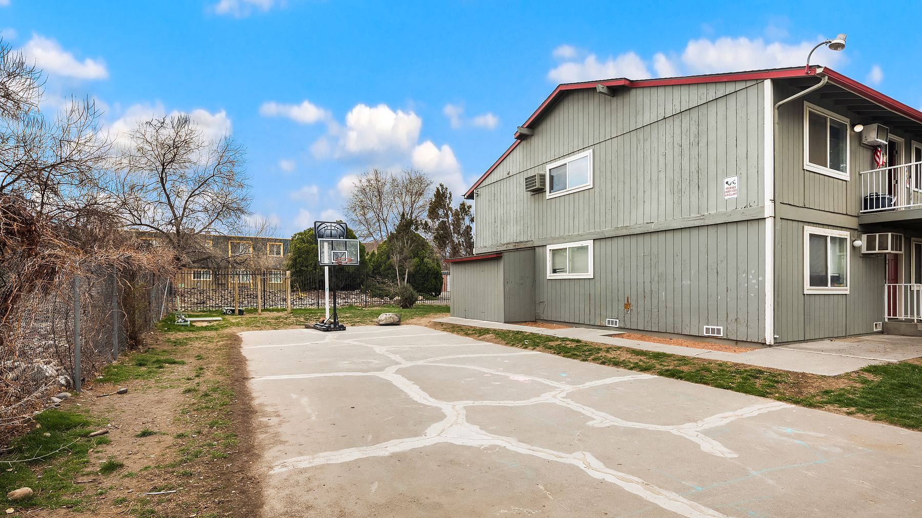 Apartment building beside a curved road under a blue sky with trees and a signpost