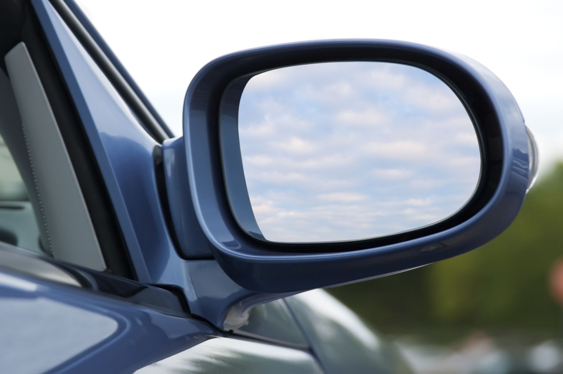 A close up of a side view mirror on a blue car